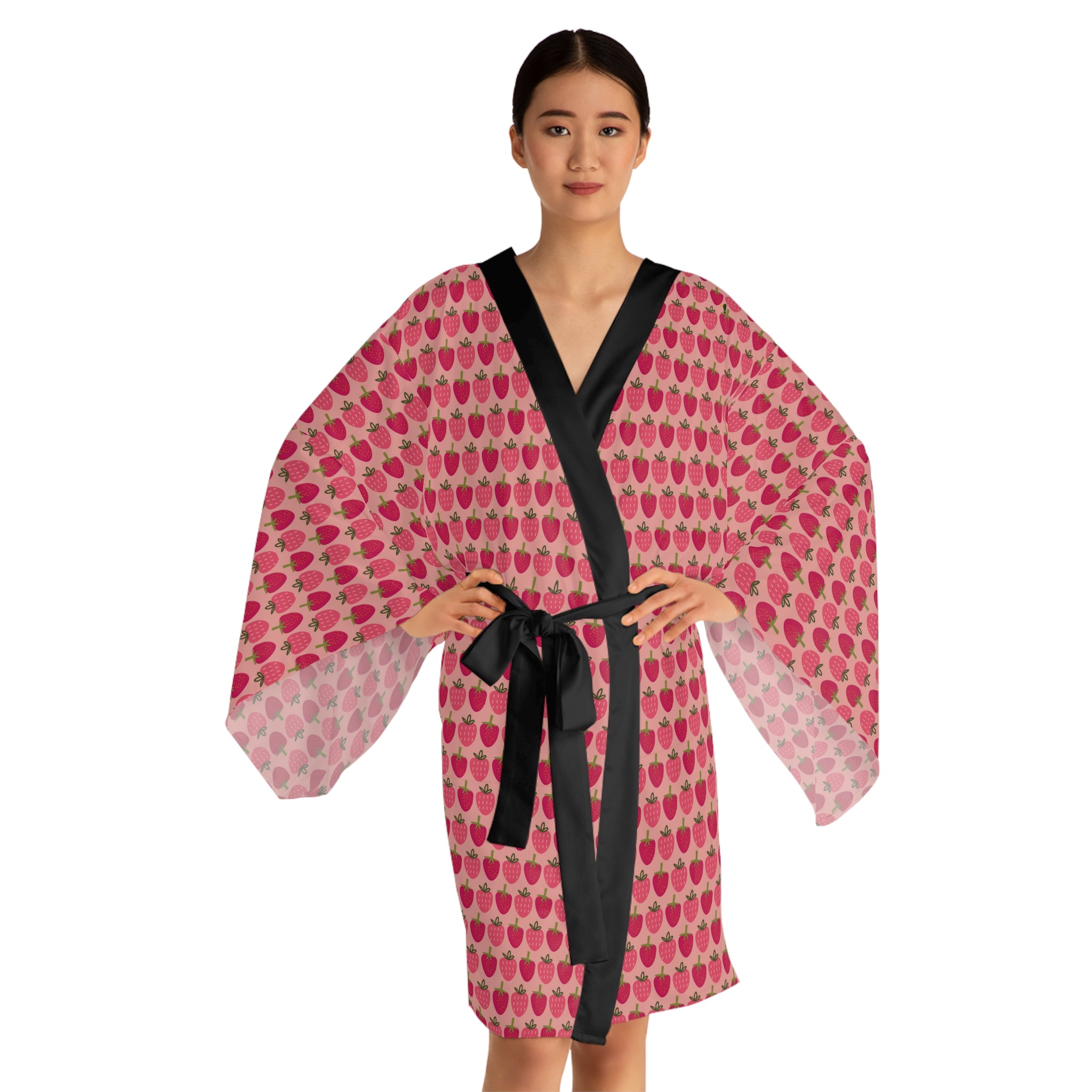 Woman wearing a pink and red patterned robe with a black belt on a white background