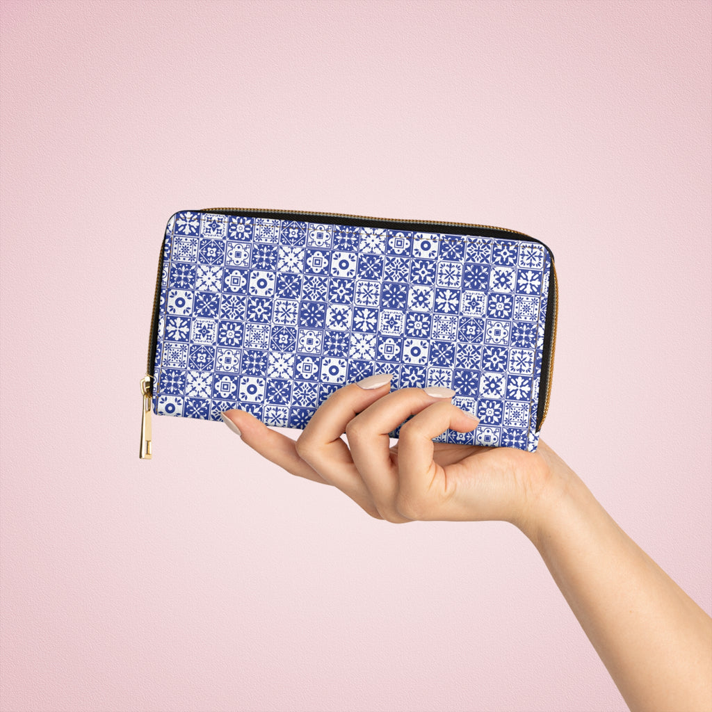 Hand holding a blue and white patterned wallet against a pink background