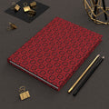 Red patterned notebook with gold and black office supplies on a dark surface