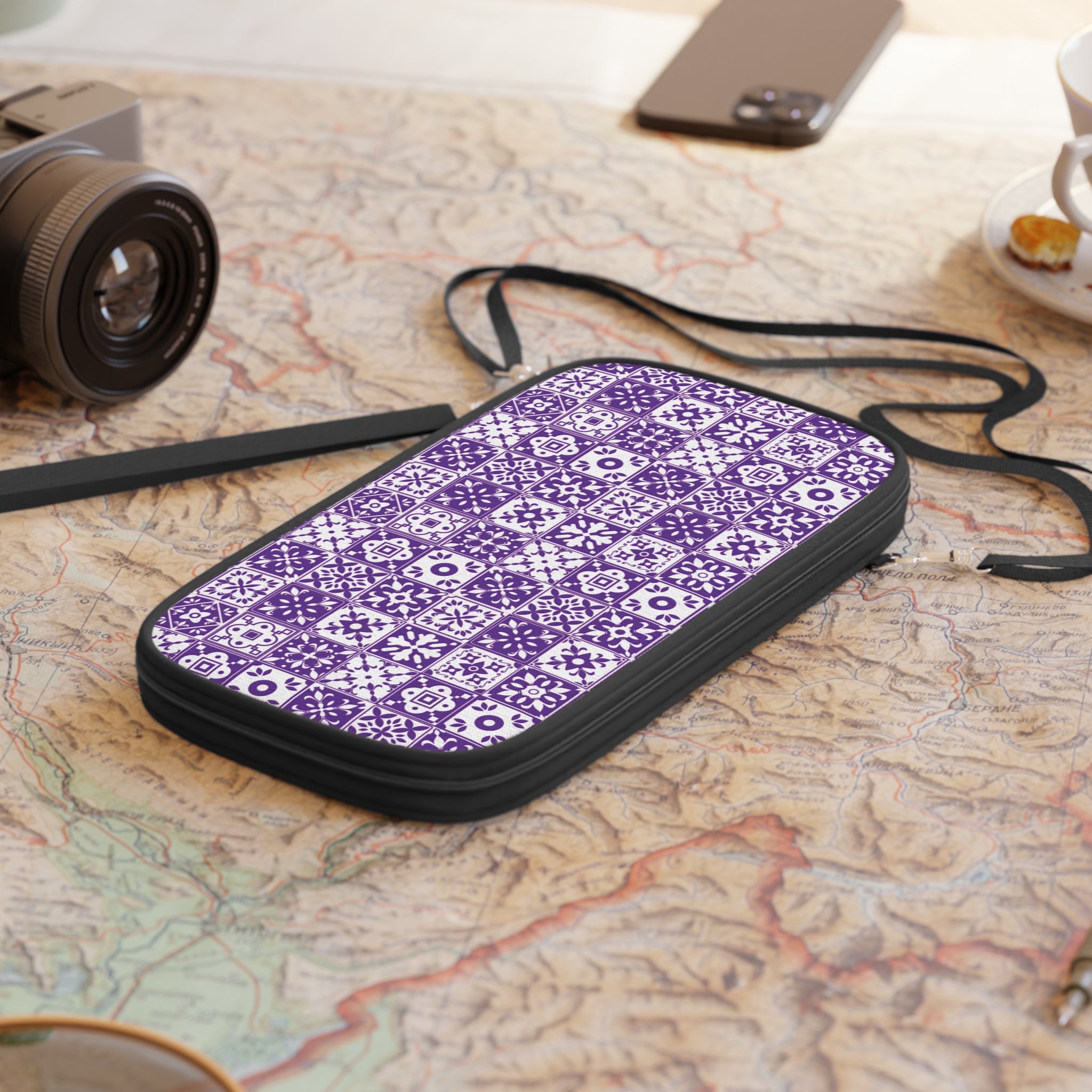 Purple patterned travel wallet on a map with a camera and phone in the background
